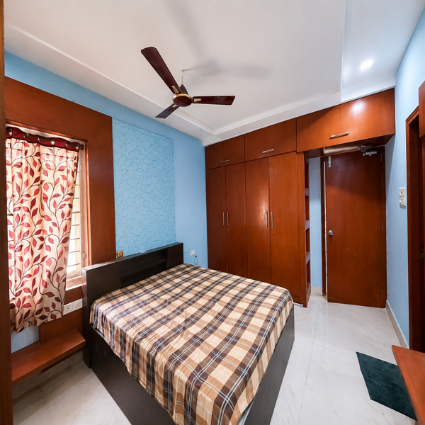 bright bedroom, modern bedroom interior, spacious bedroom, furnished bedroom, cozy sleeping space, double bed, queen size bed, floral bedspread, colorful bedroom, blue bed frame, turquoise furniture, pastel bedroom, lavender wall, mint green wall, built in wardrobe, fitted wardrobe, bedroom storage, overhead cabinets, open shelving, dressing storage, contemporary home, residential interior, elegant bedroom design, stylish sleeping room, comfortable bedroom, well lit bedroom, ceiling fan, recessed lighting, glossy flooring, marble effect floor, decorative accent wall, textured wall panel, attached bathroom, ensuite bathroom, bedroom with wardrobe, organized living space, private bedroom, rental bedroom, rental accommodation, student housing, student room, students, business professionals, working professionals, office goers, bachelor living, corporate accommodation, co living space, urban lifestyle, independent living, move in ready room, comfortable rental home, modern accommodation.